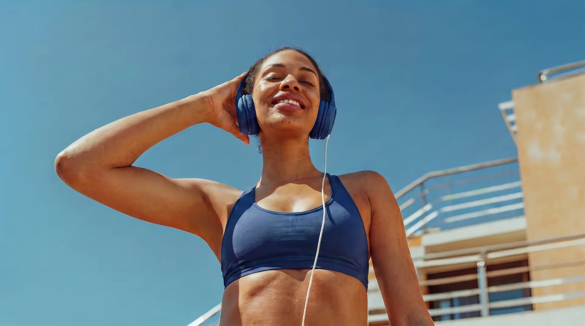 Mulher sorrindo com fones de ouvido depois do treino em um dia de sol